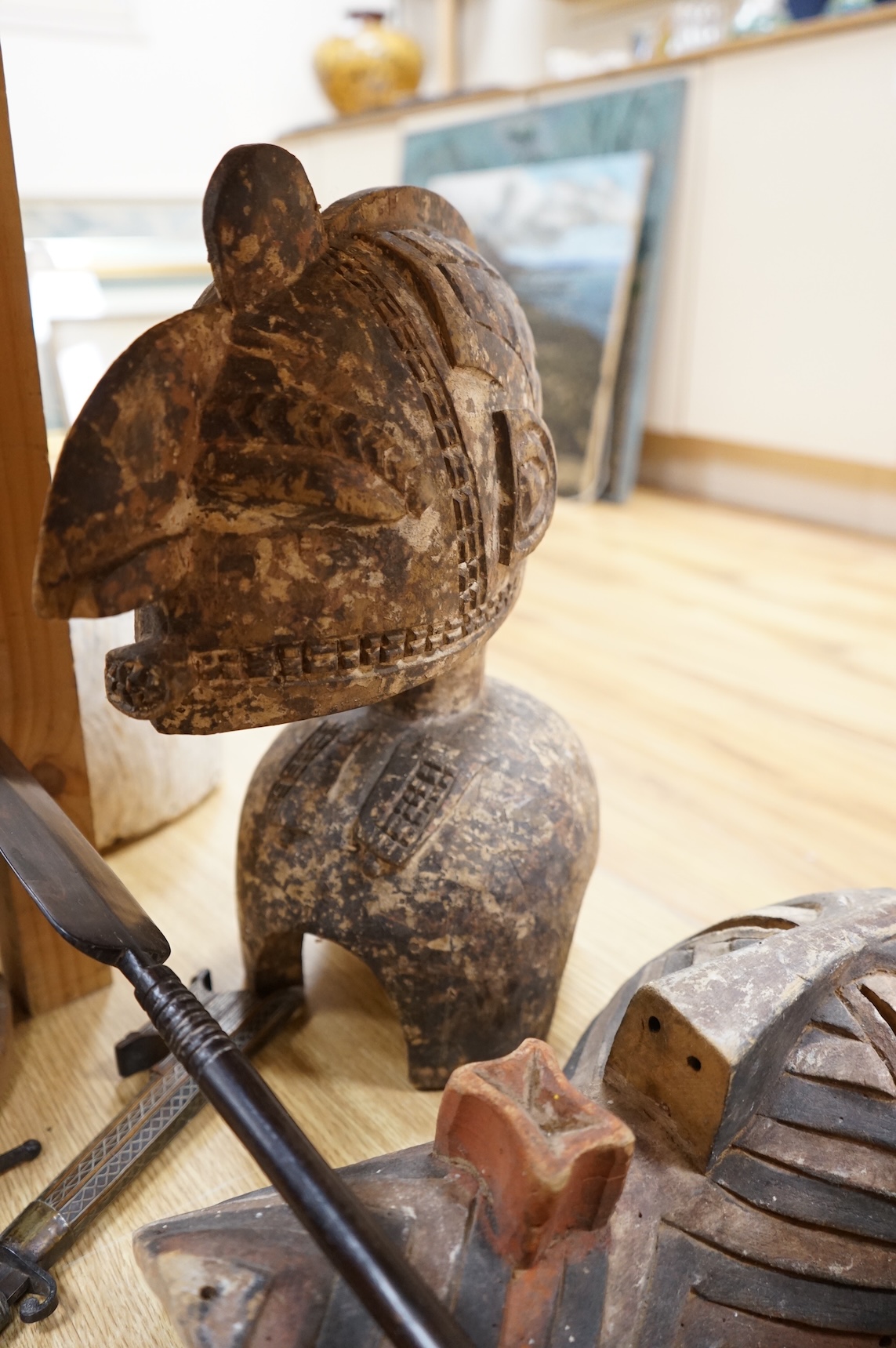 An eclectic group of tribal carvings to include a stool, various weapons, masks, etc, largest mask 52cm high
